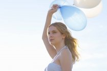 Portrait of young woman holding up balloons — Stock Photo