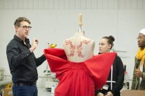 Profesor de diseño de moda evaluar el trabajo de los estudiantes - foto de stock
