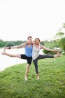 Pareja practicando yoga por agua - foto de stock