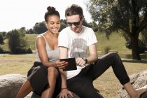 Junges Paar nutzt digitales Tablet im Park — Stockfoto