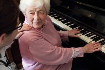 Доктор смотрит, как пожилая женщина играет на пианино — стоковое фото