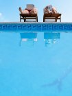 Couple sunbathing by swimming pool — Stock Photo