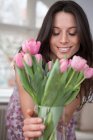 Середня доросла жінка тримає вазу з рожевих квітів — стокове фото