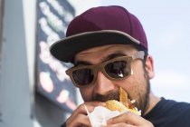 Male customer eating hamburger from fast food van — Stock Photo