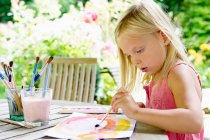 Small Girl painting with paintbrush outdoors — Stock Photo