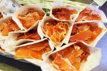 Cured ham in paper bundles — Stock Photo