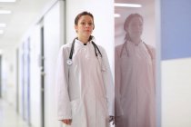 Portrait of young female doctor standing in hospital corridor — Stock Photo