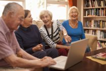 Amis masculins et féminins seniors avec ordinateur portable dans la villa de retraite — Photo de stock