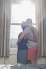 Mitte erwachsenes Paar, umarmt, Blick aus dem Fenster, Rückansicht — Stockfoto