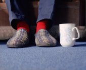 Homem pés em chinelos com caneca de chá — Fotografia de Stock