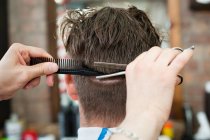 Vue arrière du jeune homme coiffé dans un salon de coiffure — Photo de stock