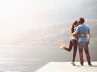 Young woman kissing boyfriend on pier at Lake Mergozzo, Verbania, Piemonte, Italy — Stock Photo