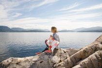 Frau sitzt mit Drachen auf Felsen am Meer — Stockfoto