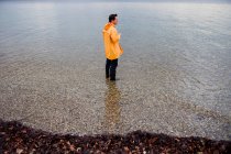 Man in raincoat in shallow water — Stock Photo