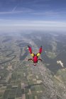 Female skydiver free falling upside down over Grenchen, Berne, Switzerland — Stock Photo