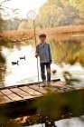 Boy standing on pier holding fishing nets, portrait — Stock Photo