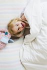 Portrait of little girl lying in bed with toy elephant — Stock Photo