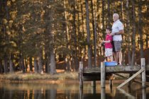 Niño pescando con el abuelo en el lago - foto de stock