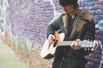 Musician playing guitar by canal wall, Milan, Italy — Stock Photo