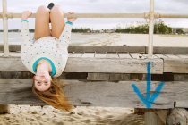 Junge Frau hängt kopfüber von Seebrücke — Stockfoto