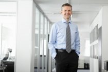 Портрет зрілого бізнесмена в офісі, руки в кишенях — стокове фото