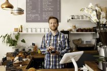 Portrait de serveur de café avec machine à cartes derrière le comptoir — Photo de stock