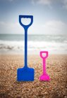 Plastic shovels in pebbly beach — Stock Photo