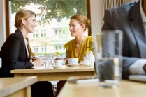 Two young female friends chatting in cafe — Stock Photo