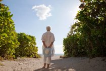 Vista posteriore della donna anziana in piedi sulla spiaggia — Foto stock