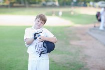 Portrait of boy wearing cricket gloves and holding helmet — Stock Photo