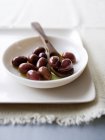 Каламата оливки с маслом и деревянной ложкой в тарелке — стоковое фото