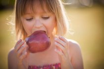 Girl eating apple outdoors — Stock Photo