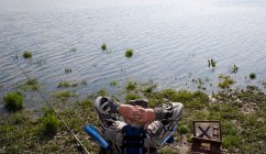 Вид сзади пожилого человека, ловящего рыбу на реке — стоковое фото