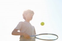 Rapaz saltando bola em raquete de tênis — Fotografia de Stock
