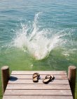 Flip flops on wooden deck by lake — Stock Photo