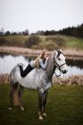 Дівчина лежить на коні в полі — стокове фото
