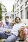 Coppia seduta su divano vintage in giardino e scattare selfie smartphone — Foto stock