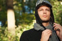 Porträt eines Mannes mit Hut und Schal, der im herbstlichen Wald wegsieht — Stockfoto