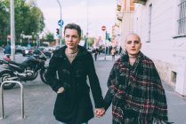 Jeune couple lesbienne marchant le long de la rue de la ville tenant la main — Photo de stock