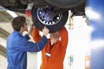Estudantes de mecânica da faculdade inspecionando roda de carro na garagem de reparação — Fotografia de Stock