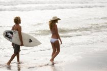 Бойфренд и девушка прогуливаются по пляжу на закате — стоковое фото