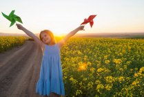 Girl playing with pinwheels outdoors — Stock Photo