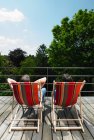 Rear view of couple enjoying sun in armchairs — Stock Photo