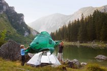 Father and son pitching a tent by lake — Stock Photo