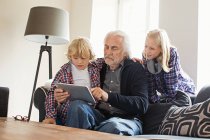 Дедушка с помощью цифровой планшет с внуками — стоковое фото
