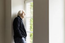 Porträt eines älteren Mannes, der aus dem Fenster schaut — Stockfoto