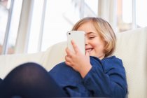 Молода дівчина використовує смартфон на дивані — стокове фото