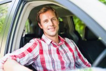 Sonriente hombre sentado en el coche - foto de stock