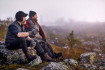 Senderistas relajándose con café en campo rocoso, Sarkitunturi, Laponia, Finlandia - foto de stock