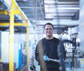 Portrait of engineer holding part in factory — Stock Photo